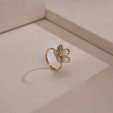 A modern 14 KT yellow gold ring, gross weight 2.554g, featuring a central cluster of brilliant round EF VVS diamonds, totaling 0.300 carats, set on a polished band. The ring is angled slightly on a soft, dark textured surface, with subtle lighting highlighting its intricate sparkle and sleek design.