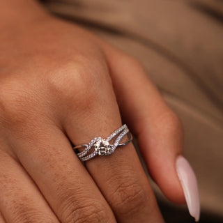 A close-up top of a female ring of size 12, on a model, showcasing a contemporary twist design with intertwining diamond-encrusted bands surrounding a brilliant round centre lab-grown diamond. Crafted in 14 KT  white gold, the total diamond carat weight is 0.73 carats with a solitaire of 0.45 carats and the weight of the product is 3.28 grams, creating a dazzling and intricate look. The split shank style adds an elegant, free-flowing appearance.