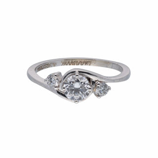 On a white background, A close-up top of a female ring of size 12, on a model, showcasing a contemporary twist design with an intertwining diamond of a trinity. Crafted in 14 KT white gold, the total diamond carat weight is 0.65 carats with a solitaire of 0.51 carats and the weight of the product is 2.15 grams, creating a dazzling and intricate look