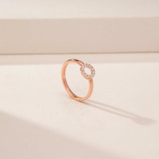 Angled view of a 14KT Rose Gold diamond ring with a circular pavé-set open centre and plain band.