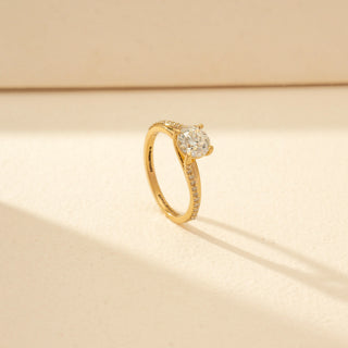 Angled view of Round Solitaire Diamond Ring in 14KT Yellow Gold, featuring a round brilliant-cut diamond and pavé-set curved bands.