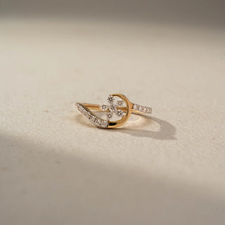 Front view of a floral diamond ring in 14 KT Yellow Gold, featuring a delicate flower cluster of round lab-grown diamonds framed by a graceful crescent-inspired pavé diamond design, displayed against a beige backdrop.