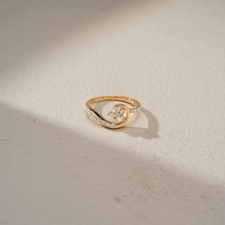 Top view of a floral diamond ring in 14 KT Yellow Gold, featuring a delicate flower cluster of round lab-grown diamonds framed by a graceful crescent-inspired pavé diamond design, displayed against a beige backdrop.