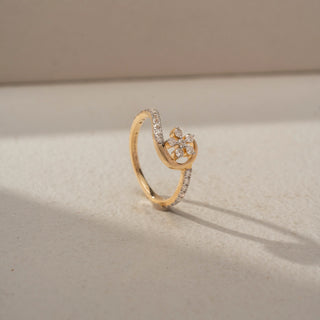 Angled view of a floral diamond ring in 14 KT Yellow Gold, featuring a delicate flower cluster of round lab-grown diamonds framed by a graceful crescent-inspired pavé diamond design, displayed against a beige backdrop.