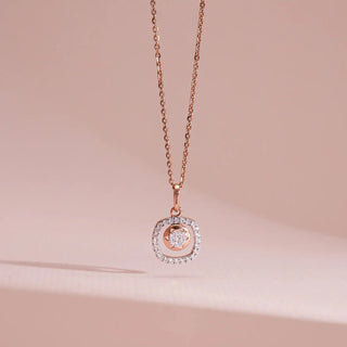 Elegant product display of a Réia lab grown diamonds pendant necklace in rose gold, featuring a square halo of round-cut diamonds with a floating centre stone, set against a soft blush background.