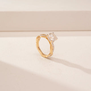 Angled view of a 14KT Yellow Gold diamond ring, featuring a round centre diamond and twisted diamond-set band.