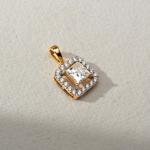 Top view of a gold square halo pendant featuring a princess-cut center Diamond surrounded by sparkling accent stones, displayed on a soft neutral surface in natural light.