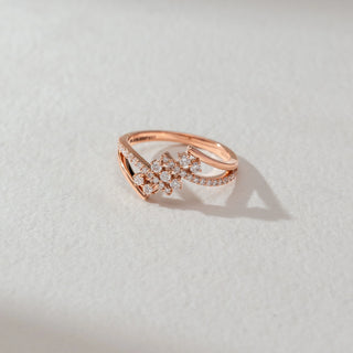 Top view of floral cluster diamond ring in rose gold, featuring round lab-grown diamonds in a blooming cluster with split diamond-studded bands. Set on a soft neutral surface, it reflects delicate elegance.