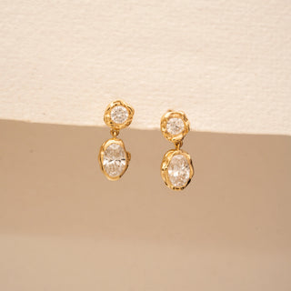 Front view of 14KT Yellow Gold drop earrings with round and oval diamonds in organic bezel settings.
