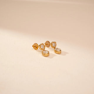 Top view of 14KT Yellow Gold drop earrings with round and oval diamonds in organic bezel settings.