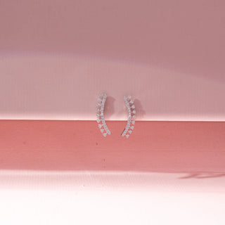 Front view of 14KT White Gold diamond ear climbers featuring a curved design with a row of round diamonds and delicate diamond accents.