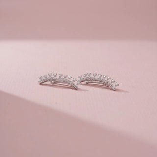 Angled view of 14KT White Gold diamond ear climbers featuring a curved design with a row of round diamonds and delicate diamond accents.