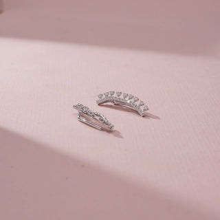 Close-up  view of 14KT White Gold diamond ear climbers featuring a curved design with a row of round diamonds and delicate diamond accents.