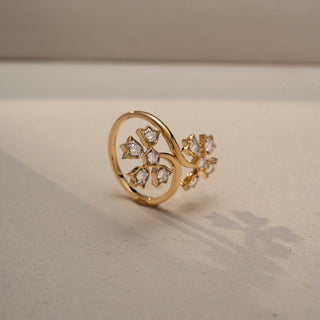 Angled view of a floral wrap ring in 14 KT Yellow Gold, featuring star-shaped motifs set with round lab-grown diamonds along an elegant open-band design, displayed against a beige backdrop.