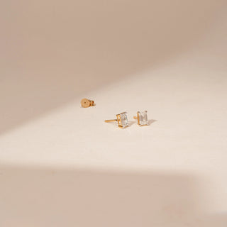 Angled view of 14KT Yellow Gold diamond earrings featuring rectangular-cut diamonds in four-prong stud settings.