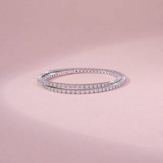 Top view of a 14KT white gold bracelet featuring round-cut diamonds, set against a pink background.