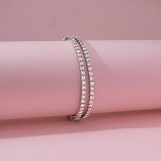 Side view of a 14KT white gold bracelet featuring round-cut diamonds, set against a pink background.