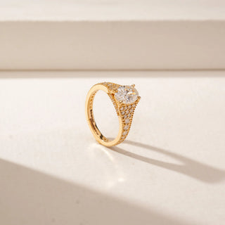 Angled view of a 14KT Yellow Gold diamond ring featuring an oval centre diamond, pavé-set shoulders and intricate diamond detailing across the wide band.