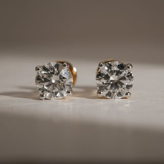 Front-facing view of Signature Solo Diamond Stud Earrings crafted in 14KT hallmarked rose gold. Each earring showcases a brilliant round-cut lab grown diamond of EF colour and VVS clarity, secured in a four-prong setting. The studs feature bombay screw closures for comfort, emphasizing the solitaire sparkle.
