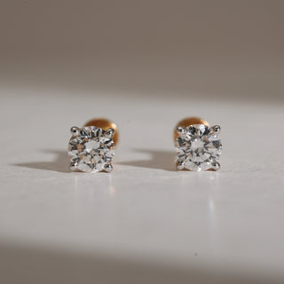 Front-facing view of Signature Solo Diamond Stud Earrings crafted in 14KT hallmarked rose gold. Each earring showcases a brilliant round-cut lab grown diamond of EF colour and VVS clarity, secured in a four-prong setting. The studs feature bombay screw closures for comfort, emphasizing the solitaire sparkle.