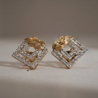 Front view of Art Deco Statement Diamond Stud Earrings on beige background. Bold interlocked square design with golden leaf accents, crafted in 14KT yellow gold. Adorned with EF VVS lab grown diamonds totaling 0.46 carats, largest 0.01 carats. Earrings weigh 2.913 grams, fitted with Bombay screw backs.