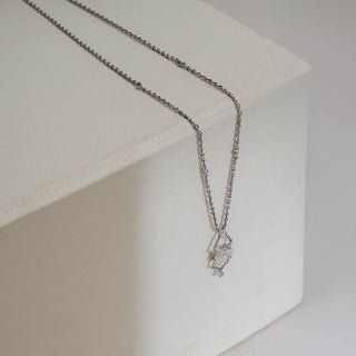 Dainty Infinity Solitaire Drop Necklace in white gold displayed draped over a textured block, featuring a delicate 14 KT chain with a solitaire diamond drop pendant of EF colour, VVS clarity, 0.72 carats, adding refined sparkle.