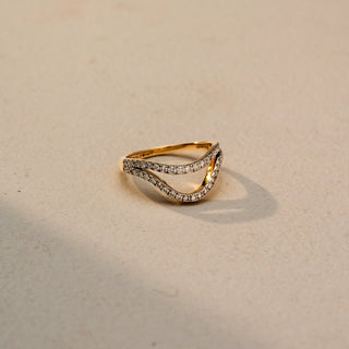 Side view of a curved diamond wedding band in White Gold, featuring pavé-set lab-grown diamonds along a graceful V-shaped silhouette, displayed against a beige backdrop.