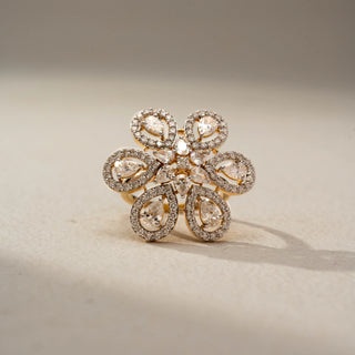 Front view of a floral diamond statement ring in 14 KT Yellow Gold, featuring pear-shaped lab-grown diamonds framed by pavé-set halos in an intricate six-petal flower design, displayed against a beige backdrop.