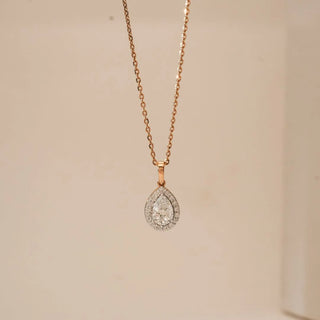 Front view of Classic Pear Halo Diamond Pendant in 18KT Rose Gold, featuring a pear-cut centre diamond encircled by a sparkling halo, suspended from a delicate rose gold chain against a soft beige backdrop.