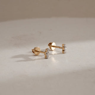 Front view of Sleek Diamond Trio Studs in 14KT Yellow Gold on beige background, featuring three round EF VVS diamonds totalling 0.094 carats for minimalist everyday elegance.