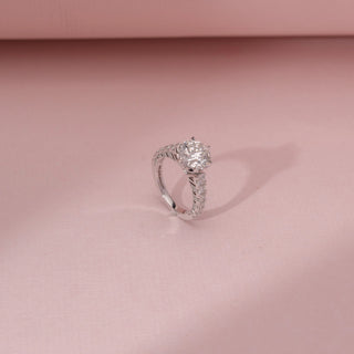 Angled view of a 14KT White Gold diamond ring with a round centre diamond, six-prong setting and diamond-set shoulders.
