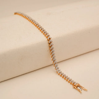 Angled view of Reia’s 14 KT Yellow Gold Diamond-Studded Chevron Link Bracelet. Captured on a cream backdrop, it highlights the warm gold foundation and the natural fire of the diamonds.