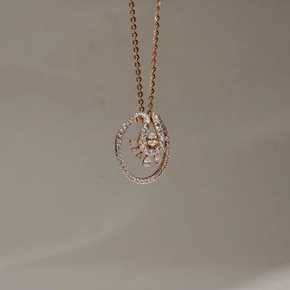 Side view of a rose gold oval pendant necklace with a pavé diamond frame and intricate diamond-accented centerpiece, suspended on a fine chain against a soft neutral background.