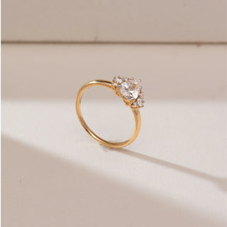 Side angle view of 14KT yellow gold ring featuring a round brilliant centre diamond with marquise-shaped cluster side accents on a slim polished band.