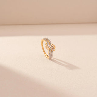 Angled view of a 14KT yellow gold ring featuring round-cut diamonds in an interlocking wave design, set against a beige background.