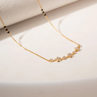 Angled view of a 14KT Yellow Gold diamond mangalsutra featuring a curved bar with round-shaped diamond clusters and delicate chain detailing.