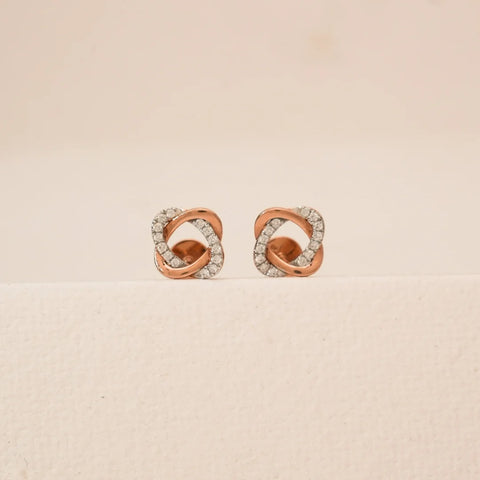 Front view of rose gold knotted diamond stud earrings featuring interlaced loop design accented with pavé-set round lab-grown diamonds, displayed on a neutral studio surface.