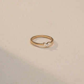 Side view of a Duo Diamond Heart Ring in 14KT Yellow Gold, two round lab-grown diamonds in a heart cluster on a slim band. Beige backdrop highlights subtle sparkle.