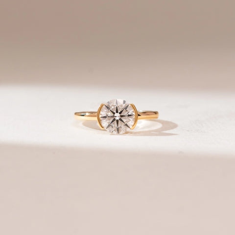 Front view of 14KT yellow gold ring featuring a round brilliant-cut centre diamond in a sleek bezel-style setting on a polished minimalist band.