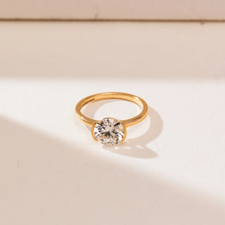 Angled top view of 14KT yellow gold ring featuring a round brilliant-cut centre diamond in a sleek bezel-style setting on a polished minimalist band.