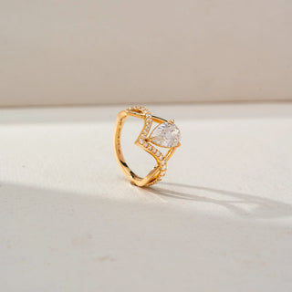 Side view of a yellow gold ring featuring a pear-cut diamond in an open geometric setting, accented with pavé diamonds along the sculpted band for a modern, elegant look.