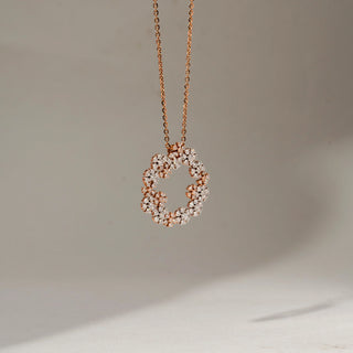 Side view of a rose gold floral wreath pendant necklace, showcasing layered diamond clusters and the pendant’s dimensional profile against a soft neutral background.