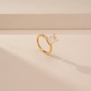 Angled view of Dazzling Emerald Diamond Solitaire Ring in 14KT Yellow Gold, featuring an emerald-cut lab-grown diamond.