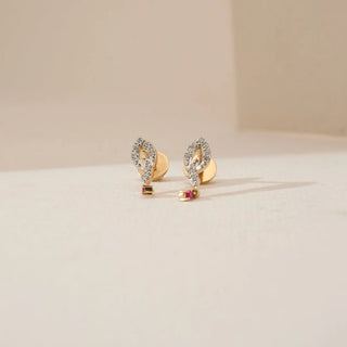 Front view of marquise-inspired diamond earrings with pavé-set lab grown diamonds and delicate ruby drop accents in yellow gold, placed on a soft neutral display surface.