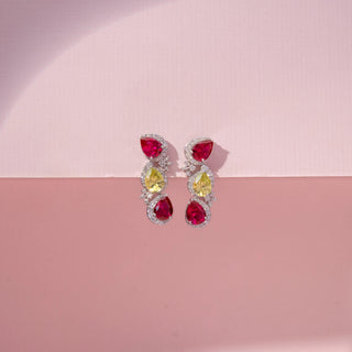 Front view of ruby, yellow sapphire and lab-grown  round cut diamond drop earrings in 14 KT white gold, featuring pear-shaped ruby and yellow sapphire gemstones framed by pavé-set diamond halos with floral diamond accents.
