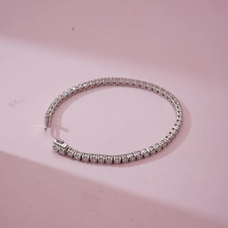 Top view of Classic Silver Tennis Diamond Bracelet in white gold, showcasing a continuous line of round lab-grown diamonds arranged in a flexible setting, displayed on a soft pink surface.