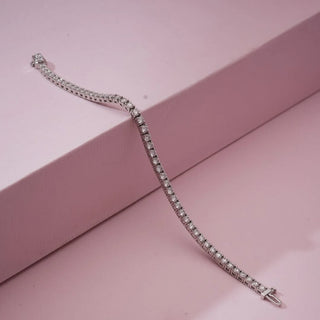 Angled view of Classic Silver Tennis Diamond Bracelet in white gold, featuring a continuous row of round lab-grown diamonds draped over a soft pink display block, emphasizing fluid sparkle and flexibility.