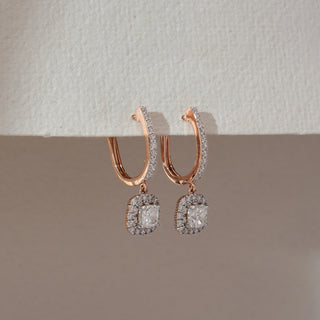 Side view of rose gold hoop drop earrings with diamond-lined outer edge, featuring a square halo lab-grown diamond pendant. Captured against a soft beige textured background with subtle shadows.