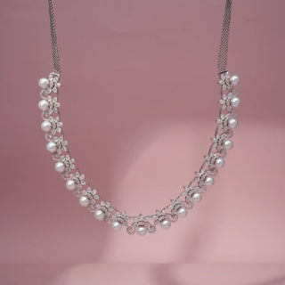 Front view of a pearl and lab-grown diamond necklace in 14KT White Gold, featuring round pearls with floral diamond motifs. Captured against a pink backdrop, the graceful design radiates timeless elegance.