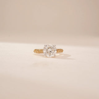 Angled view of a 14KT Yellow Gold diamond ring, featuring a round centre diamond and diamond-set inner band.